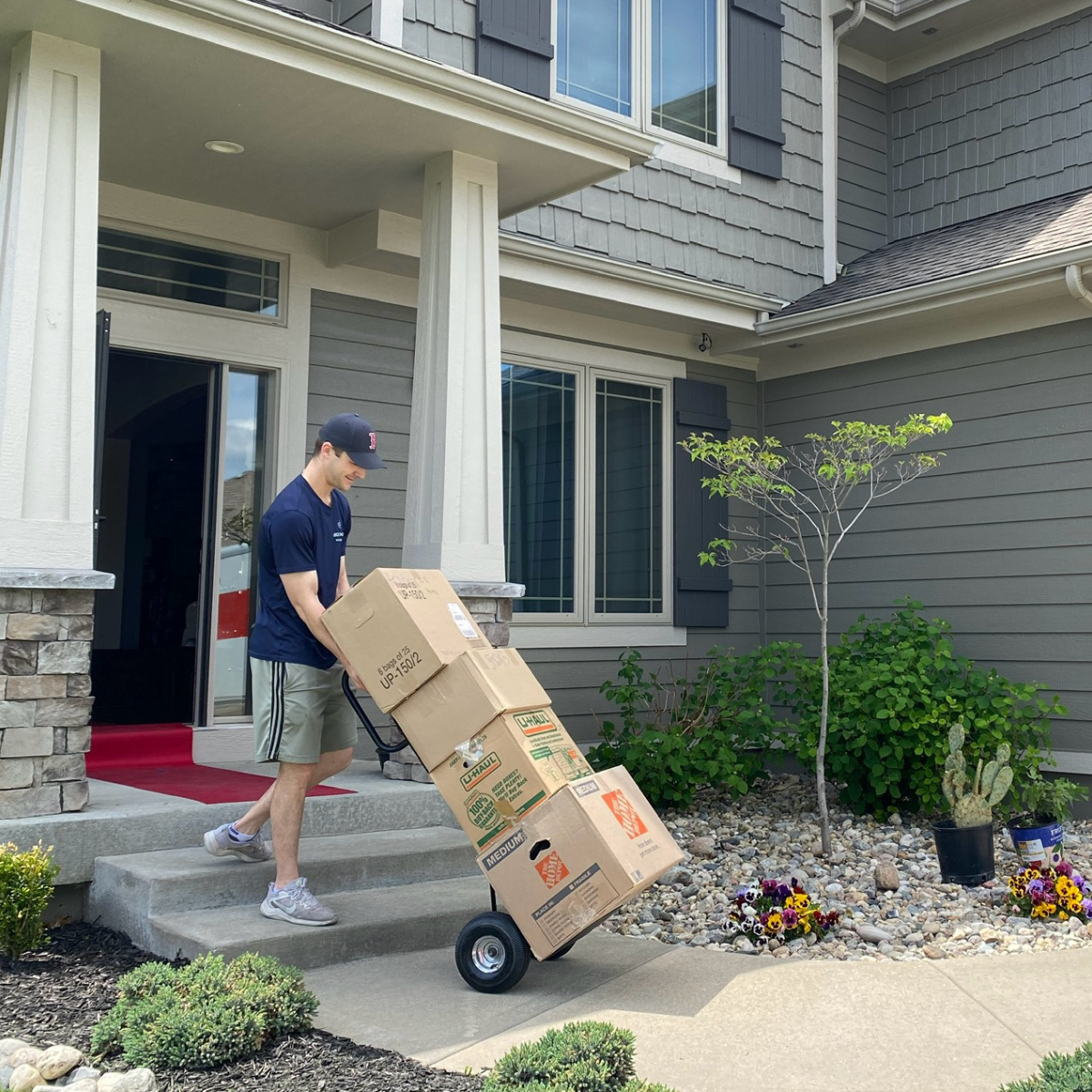 A Box N Haul mover carrying stacked moving boxes up to a Overland Park home on a hand truck