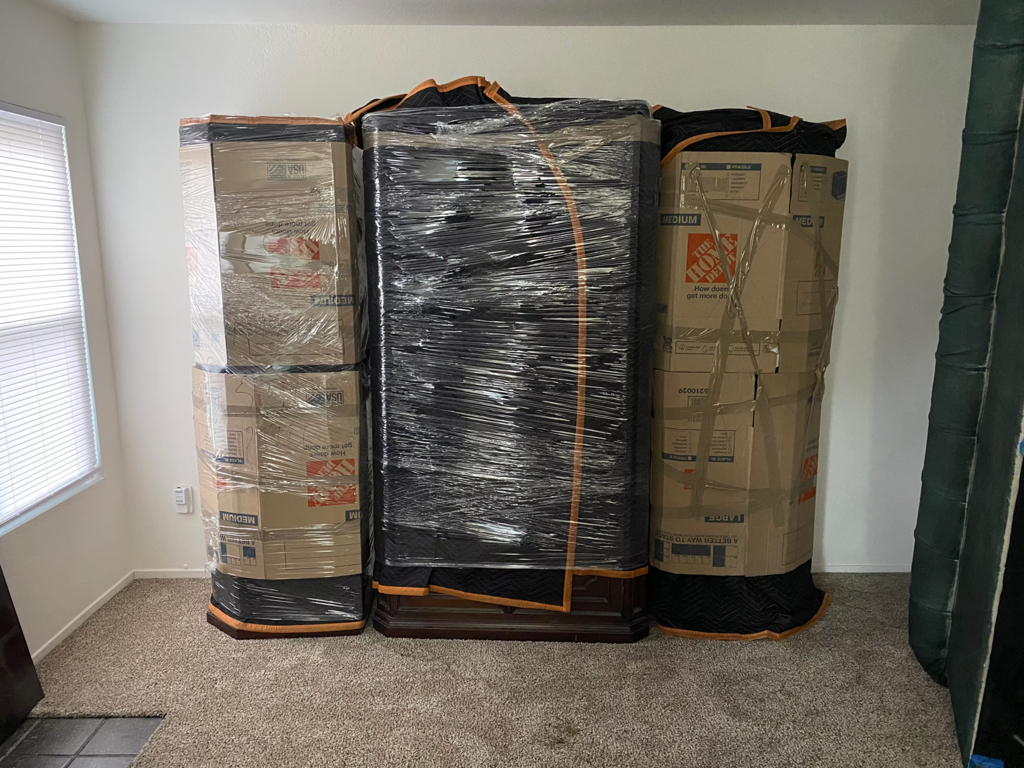 Carefully wrapped and padded furniture and boxes staged against a wall, ready to be moved.