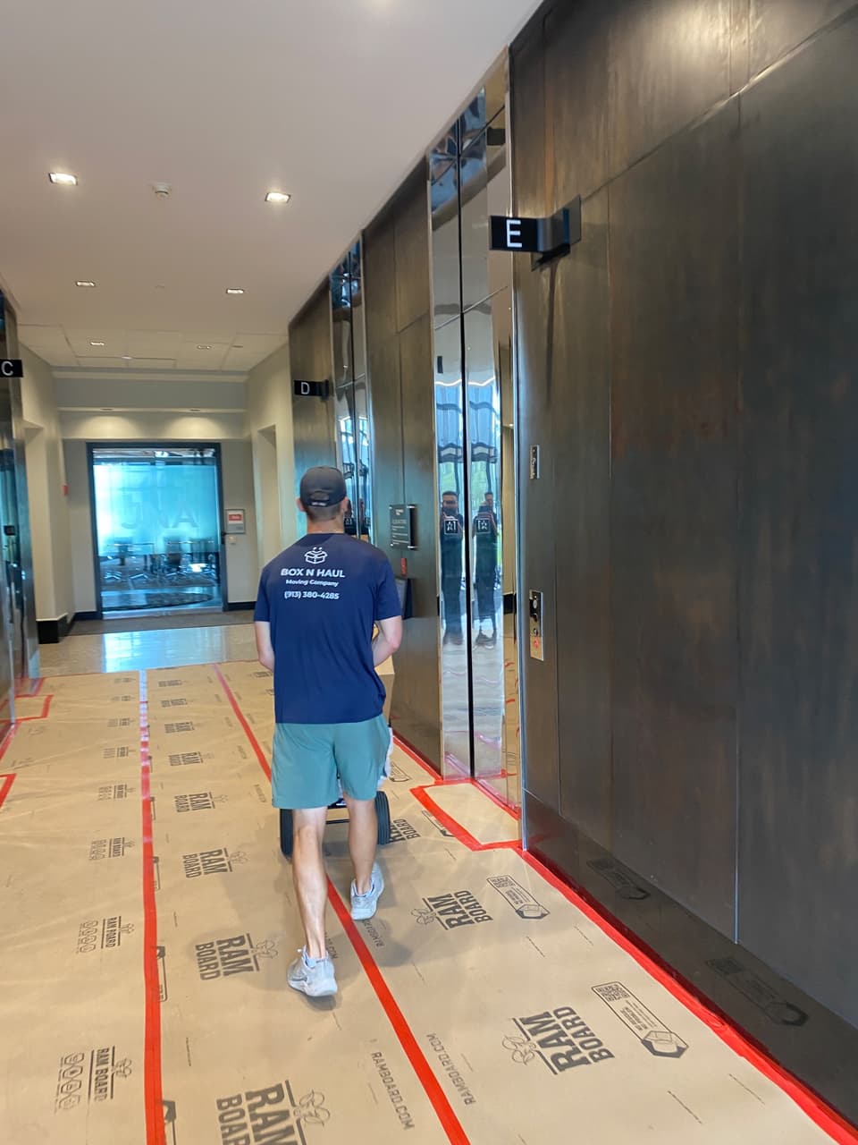 Box N Haul mover wheeling a loaded dolly down an office corridor during a commercial move