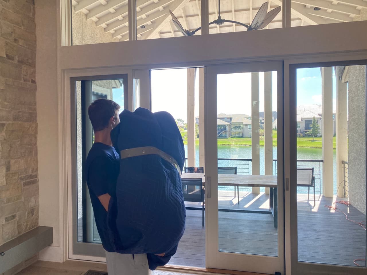 Box N Haul mover carrying blanket-wrapped furniture through a Kansas City home toward patio doors