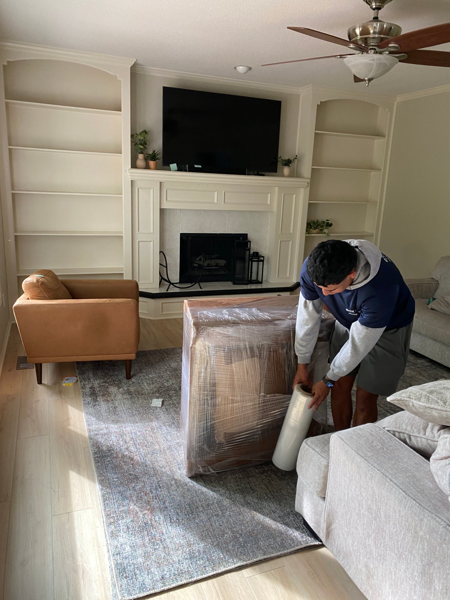 Box N Haul mover wrapping a chair in plastic in a living room, getting a home ready to show